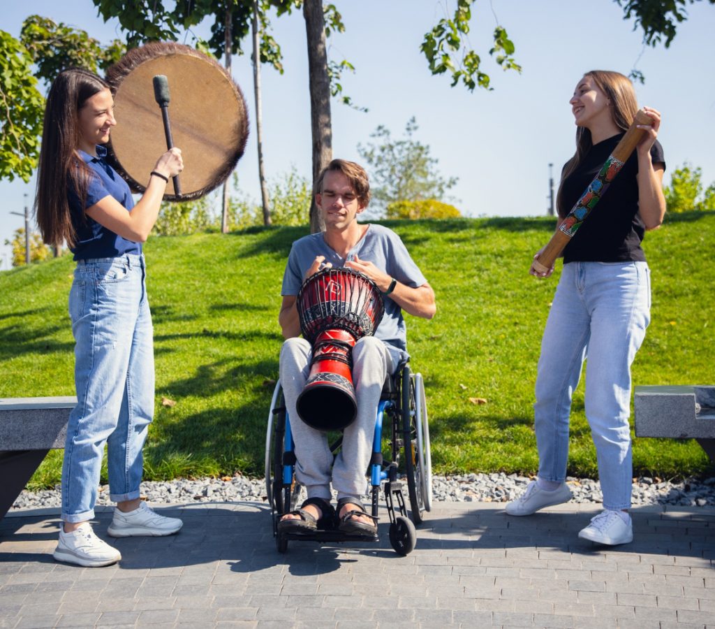 happy-handicapped-man-wheelchair-spending-time-with-friends-playing-live-instrumental-music-outdoors